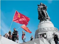 ?? MARKUS SCHREIBER THE ASSOCIATED PRESS ?? People with Soviet flags visit the Soviet war memorial in Berlin.