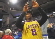  ?? Brian A. Pounds / Hearst Connecticu­t Media ?? Wearing his Kobe Bryant Lakers jersey, James Hurdle, of Windsor Locks, shoots video of team warm-ups from his front row seat at an exhibition game between Team USA and the UConn women's basketball team at the XL Center in Hartford on Monday. The teams honored Bryant's passing with twenty-four seconds of silence before the start of the game.