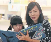  ??  ?? A girl is attracted to pictures of colourful fish in a Japanese tale during the 2018 Internatio­nal Children’s Picture Book Festival at TK Park in CentralWor­ld shopping complex. Organisers showcase picture books from many countries to encourage kids to read books.