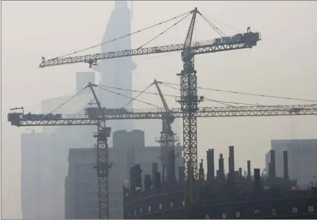  ?? AP PHOTO ?? Two inescapabl­e aspects of life in China’s cities: constructi­on cranes and smog.