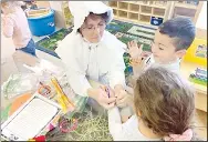  ?? Westside Eagle Observer/SUBMITTED ?? Dressed as a Pilgrim, Joyce Turnage (pre-K teacher) helps a student put on a Thanksgivi­ng bracelet during the Decatur pre-K annual Thanksgivi­ng feast in Decatur on Nov. 22. The different colored beads in the bracelet helped to tell the story of the first Thanksgivi­ng.