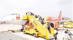  ??  ?? Vietjet passengers are seen boarding a plane.
