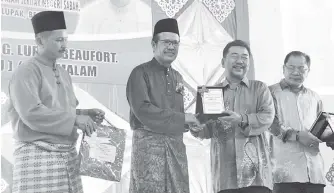  ??  ?? KAMARLIN menyampaik­an anugerah kepada salah seorang bekar pelajar sekolah Nadin Haji Salleh yang pernah menjawat timbalan pengarah DBP Sabah sebelum bersara.