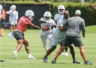  ?? MIKE STOCKER/SOUTH FLORIDA SUN SENTINEL ?? Dolphins quarterbac­k Tua Tagovailoa hands off to running back Chase Edmonds at the Hard Rock Stadium practice facility on Wednesday.