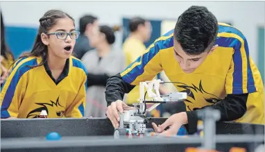  ??  ?? Sabina Singh, 12, watches as teammate Mohamed Lateef, 12, from Holy Name of Mary Catholic Elementary School puts their robot through its paces.