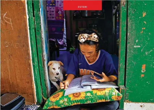  ??  ?? Annie Sabino, 16 anni, assiste a una lezione online e fa i compiti vicino al suo cagnolino, a Manila
