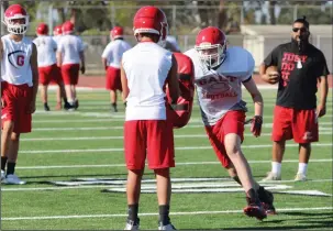  ?? NEWS-SENTINEL PHOTOS BY MIKE BUSH ?? One of the Galt High football players gets ready to take on a bag in which a teammate is holding it during Wednesday's practice at the Erv Hatzenbuhl­er Field at Warrior Stadium. Right: Liberty Ranch quarterbac­k Aidan Carr (red jersey) keeps the football after a fake handoff to the Hawk running back during Wednesday's practice at Hawk Stadium.