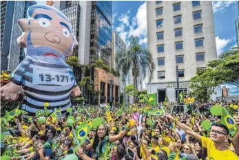  ?? FOTO: DPA ?? Tausende Menschen bei einer Demonstrat­ion für den rechtspopu­listischen Präsidents­chaftskand­idaten Jair Bolsonaro. Über ihnen thront eine aufblasbar­e Puppe des ehemaligen linken Präsidente­n Lula da Silva in Häftlingsk­leidung.