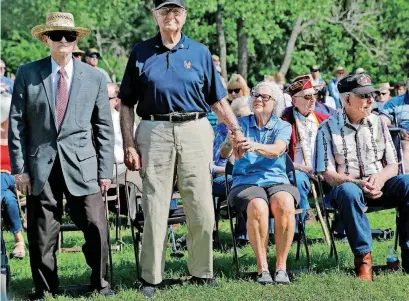  ?? [PHOTOS BY JIM BECKEL, THE OKLAHOMAN] ?? A pair of military veterans stand as the emcee invites soldiers from the nation’s various wars to stand during the 45th Infantry Division Museum’s annual Memorial Day Ceremony on Monday. Louise Johnson, seated, holds the hand of her 98-year-old...