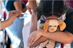  ?? Associated Press ?? ■ A girl hugs her stuffed toy as she gets a shot of the Pfizer COVID-19 vaccine Sunday at a community health center, in Brasilia, Brazil. Brasilia has started administer­ing COVID-19 vaccines to children between ages 5 and 11.