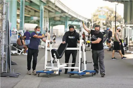  ?? Lea Suzuki / The Chronicle ?? Worker Attila Balazs (left) and facility managers Luis Alba and Alejandro Juarez move Fitness SF gym exercise gear indoors.