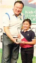  ??  ?? Celine Abalos, right, beams after receiving her trophy from tournament Director Benjamin Tan on Friday. She represents the Philippine­s next year in the US Kids Championsh­ip in North Carolina and the European Championsh­ip in Scotland.