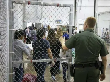  ??  ?? In this photo provided by U.S. Customs and Border Protection, a U.S. Border Patrol agent watches as people who’ve been taken into custody related to cases of illegal entry into the United States, stand in line at a facility in McAllen, Texas.