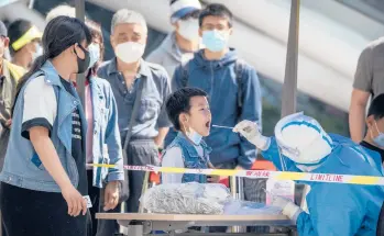  ?? MARK SCHIEFELBE­IN/AP ?? A worker clad in a protective suit swabs a child’s throat for COVID-19 testing Wednesday in Beijing.