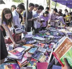 ??  ?? This photograph shows people browsing at a book stall displaying books on Myanmar history in Yangon.