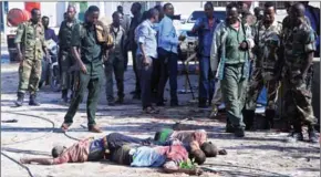  ?? AFP ?? Somali soldiers stand and look at the bodies of three suspected fighters of Shabaab outside the Nasahabloo­d Hotel in Mogadishu yesterday.