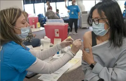  ?? Pittsburgh Post-Gazette ?? Ashley Conte, a registered nurse with Allegheny Health Network, gives Wei Wei Zhang, of Allison Park, the first dose of the Pfizer-BioNTech COVID-19 vaccine Monday at Next Tier Connect at Pittsburgh East in Monroevill­e.