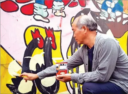  ?? SAM YEH/AFP ?? Hakka graffiti artist Wu Tsun-hsien painting a wall in the Taiwanese village of Ruan Chiao.