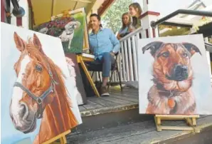  ??  ?? Teens watch as pet artist David Kennett paints along Main Street in Breckenrid­ge on July 2.