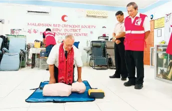  ?? ?? Chua (right) observes as Hall performs a CPR demonstrat­ion using a manikin.