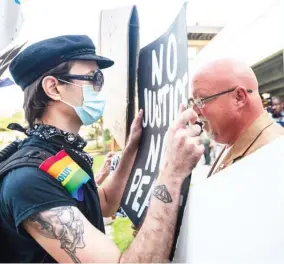  ??  ?? Two demonstrat­ors have an altercatio­n at the base of the Confederat­e monument during a protest to remove it from in front of the Harrison County Courthouse parking lot in Gulfport, Miss., Thursday, Sept. 3, 2020. (Photo by Lukas Flippo, The Sun Herald via AP)