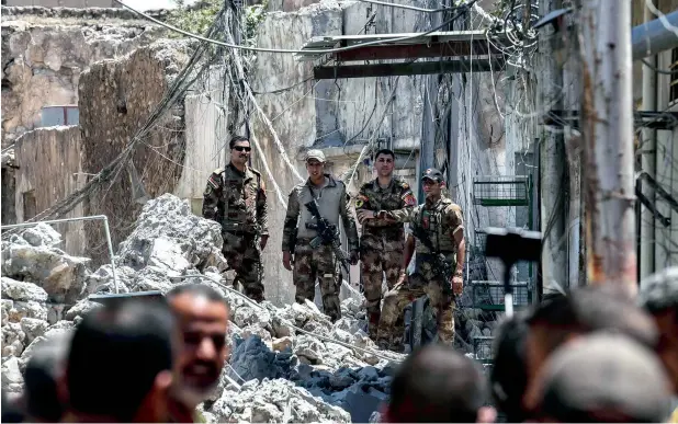  ?? — AFP ?? Iraqi forces advance through Old City of Mosul during the ongoing offensive to retake the last district held by Daesh. Buildings have been flattened and streets are filled with chunks of concrete and dust.