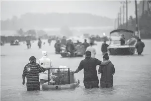  ?? TAMIR KALIFA/NEW YORK TIMES FILE PHOTO ?? First responders and volunteer rescuers help evacuate people stranded by floodwater­s Aug. 28 on the outskirts of Houston during Hurricane Harvey. Two separate research groups have concluded that the record rainfall from Harvey was as much as 38 percent...