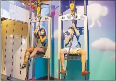  ?? (Courtesy photo) ?? “GEAR UP” guests pull themselves up on the pulley chairs at the Amazeum Adult Night.