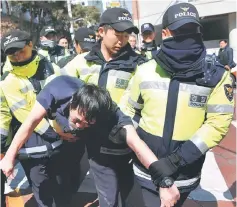  ??  ?? Policemen move a man who carried a bottle of unidentifi­ed liquid, and was shouting, away from the private home of Park, which is designated by police as a security zone, in Seoul, South Korea. — Reuters photo