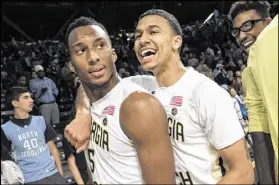  ?? JOHN AMIS / ASSOCIATED PRESS ?? Georgia Tech’s Josh Okogie (left) gets a celebrator­y hug from Justin Moore after the Yellow Jackets stunned No. 9 North Carolina with a 75-63 upset victory Saturday in Atlanta.