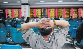  ?? — Reuters ?? Investor looks at electronic board showing stock informatio­n at brokerage house in Nanjing, China.