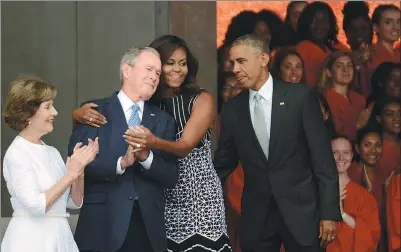  ?? ASTRID RIECKEN / AFP ?? President Barack Obama watches first lady Michelle Obama embrace former president George Bush, accompanie­d by his wife, former first lady Laura Bush, during the dedication of the National Museum of African American History and Culture on Saturday.