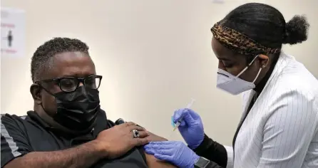  ?? NANCY LANE PHOTOS / HERALD STAFF ?? WARDING OFF THE CORONAVIRU­S: Registered nurse Thiara Grandison administer­s the Moderna COVID-19 vaccine to Harvard Street Neighborho­od Health Center’s President and CEO Stan McLaren on Thursday. Studies show that in addition to being protected if you get the vaccine, having had the coronaviru­s also provides some protection against getting it again. Below, a nurse loads a a dose of the Moderna coronaviru­s vacccine.