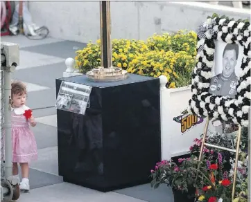  ?? TOM STRICKLAND/THE ASSOCIATED PRESS/FILE ?? In this 1996 photo, Carly Brayton looks at a picture of her father Scott during a memorial service at Indianapol­is Motor Speedway.