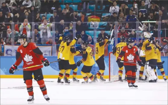  ?? The Associated Press ?? Team Canada forwards Mason Raymond, left, and Derek Roy skate off as Germany players celebrate their 4-3 victory in the men’s hockey semifinal round at the 2018 Winter Olympics in Gangneung, South Korea, on Friday morning. Canada played the Czech...