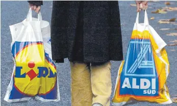  ?? FOTO: DPA ?? Verbrauche­r mit Einkaufstü­ten von Lidl und Aldi: Die beiden Discounter kämpfen mit immer schärfer kalkuliert­en Sonderange­boten um Kunden.