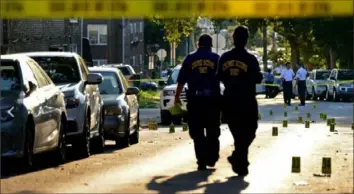  ?? Tom Gralish/Philadelph­ia Inquirer ?? Philadelph­ia police crime lab investigat­ors on the scene of a shooting in which six officers were shot Wednesday night. Evidence markers show where 36 shell casings are located at 15th and Conlyn streets in North Philly.