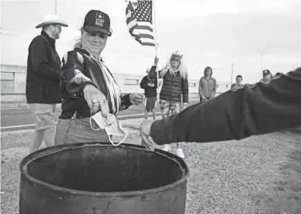  ?? COURTNEY SACCO/USA TODAY NETWORK ?? A group of people gather to burn masks along the JFK Memorial Causeway in honor of the end of the statewide mask mandate across Texas on March 10.