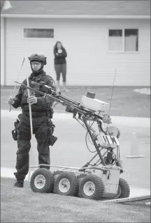  ?? Herald file photo by Tijana Martin ?? A member from the Explosive Disposal Unit takes measuremen­ts off the robot during a mental health situation along the 2500 block of Walshe Drive West in June.