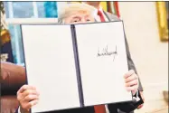  ?? Andrew Harrer / Bloomberg ?? At the White House on Wednesday, President Donald Trump holds up a signed executive order to end his policy of family separation­s at the Mexican border.