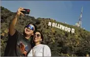  ?? Brian van der Brug Los Angeles Times ?? TOURISTS Andreas Minniti, left, and his sister Maria Pino take a selfie near the Hollywood sign.