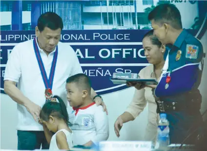  ?? SUNSTAR FOTO / AMPER CAMPAÑA ?? FLAMES. The children of PO2 Aristeo Tampus, an anti-narcotics operative of San Fernando, pay their respects to President Rodrigo Duterte after the latter gave their father the Order of Lapu-Lapu (Kampilan medal).