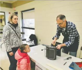  ?? LYNN GIESBRECHT ?? Jana Jedlic, left, looks on with daughter Liana Gomez as Repair Cafe volunteer Roy Dorwart attempts to fix her espresso machine at the Cathedral Neighbourh­ood Centre on Saturday.