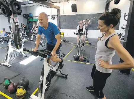  ??  ?? Lisa Sinclair helps Ovidiu Schiopu with a workout at Body Dynamics Personal Fitness on Johnson Street.