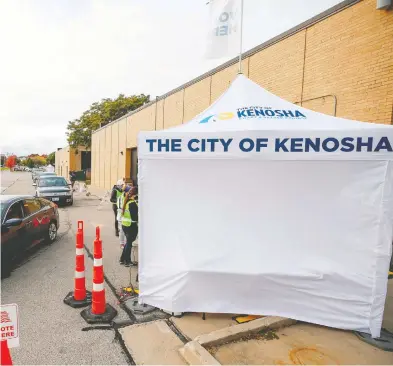  ?? KAMIL KRZACZYNSK­I / AFP VIA GETTY IMAGES FILES ?? People in their cars wait in line to cast their ballots at a drive-thru early voting location outside City Hall in Kenosha,
Wisc., for the Nov. 3 elections. Early voting kicked off Oct. 20 in Wisconsin.