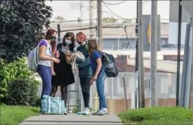  ?? Andrew Rush/Post-Gazette ?? Students wait at a bus stop Tuesday near Ambridge Area Senior High School in Beaver County on the first day of Pennsylvan­ia’s mask mandate for K-12 schools and day care centers.