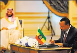 ??  ?? The Associated Press Ethiopian Prime Minister Abiy Ahmed signs a peace accord Sunday with Eritrea as Saudi Crown Prince Mohammed bin Salman looks on in in Jiddah, Saudi Arabia.