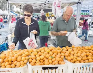  ?? David Karp ?? SHOPPERS peruse Honey Rich Apriums grown by Ken Lee in Reedley, Calif., at the Torrance farmers market last May. This location participat­es in the Food Forward nonprofit program.