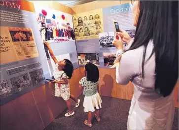  ?? Irfan Khan ?? PHUONG TRAN, 30, photograph­s her daughters, Tiffany, 5, left, and Angelina, 3, looking at a photo of their grandfathe­r, Gen. Nhut Van Tran and grandmothe­r, Lang Tran, at the Old Orange County Courthouse.