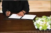  ?? DOUG MILLS / NEWYORK TIMES ?? North Korean leader Kim Jong Un signs a document at a ceremony Tuesday with President Donald Trumpon Sentosa Island in Singapore.